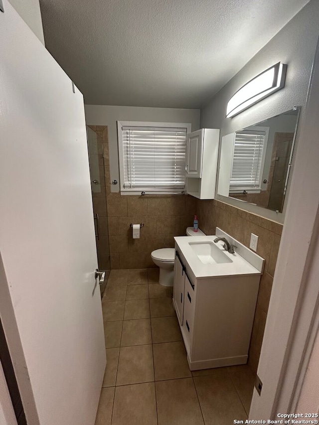 bathroom featuring tile walls, vanity, toilet, tile patterned floors, and a textured ceiling