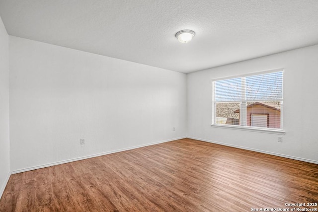 empty room with wood-type flooring and a textured ceiling