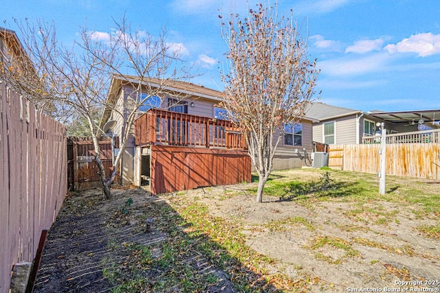 back of property with a deck, a lawn, and central air condition unit