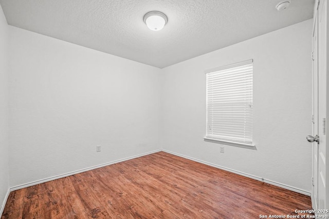 spare room with hardwood / wood-style flooring and a textured ceiling