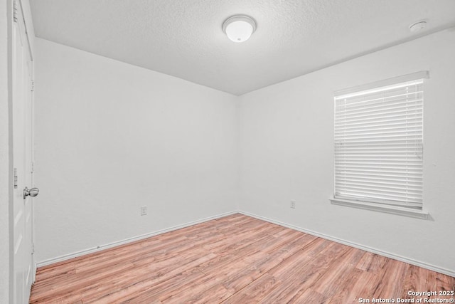 spare room featuring light hardwood / wood-style floors and a textured ceiling