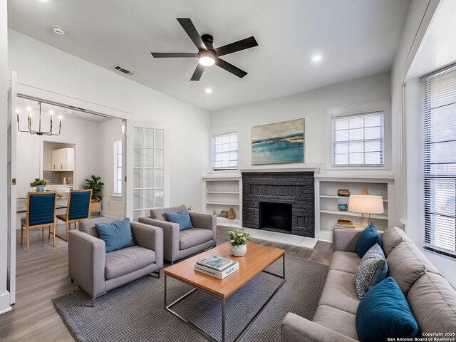 living room with a stone fireplace, plenty of natural light, and light hardwood / wood-style floors