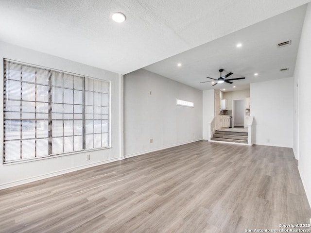 unfurnished living room with ceiling fan, a textured ceiling, and light wood-type flooring