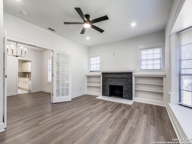 unfurnished living room featuring hardwood / wood-style flooring, ceiling fan with notable chandelier, and a fireplace