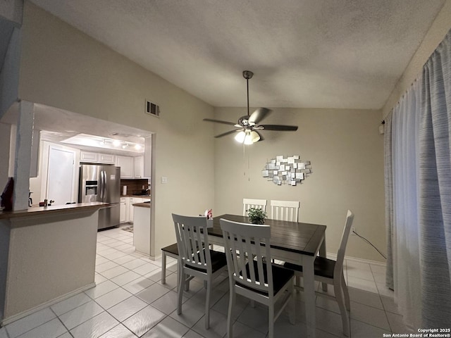 tiled dining area with a textured ceiling, vaulted ceiling, and ceiling fan