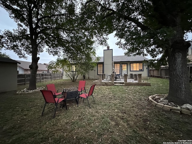 back of house featuring an outdoor fire pit and a lawn