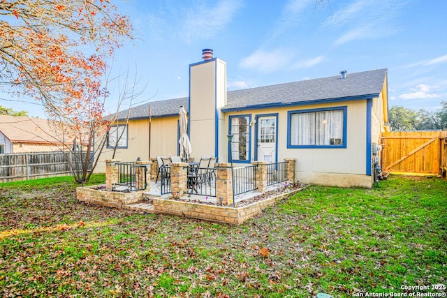 back of house with a yard and a patio