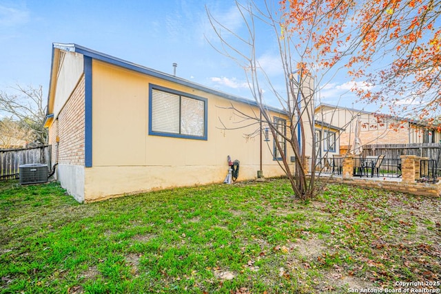 back of house featuring a yard and central air condition unit