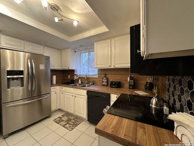 kitchen with white cabinetry, dishwasher, stainless steel fridge, and a tray ceiling