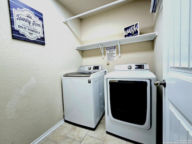 clothes washing area with light tile patterned floors and washer and clothes dryer