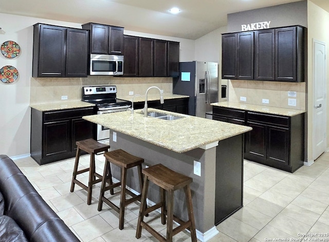 kitchen featuring sink, a breakfast bar, stainless steel appliances, tasteful backsplash, and an island with sink