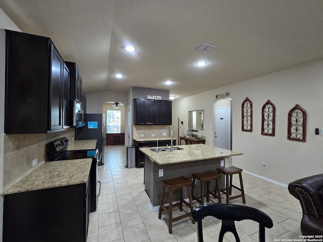 kitchen with sink, a center island with sink, appliances with stainless steel finishes, ceiling fan, and backsplash