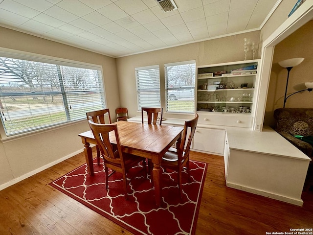 dining space featuring ornamental molding and dark wood-type flooring