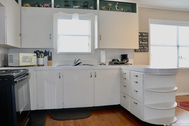 kitchen with hardwood / wood-style flooring, white cabinetry, black electric range, and sink