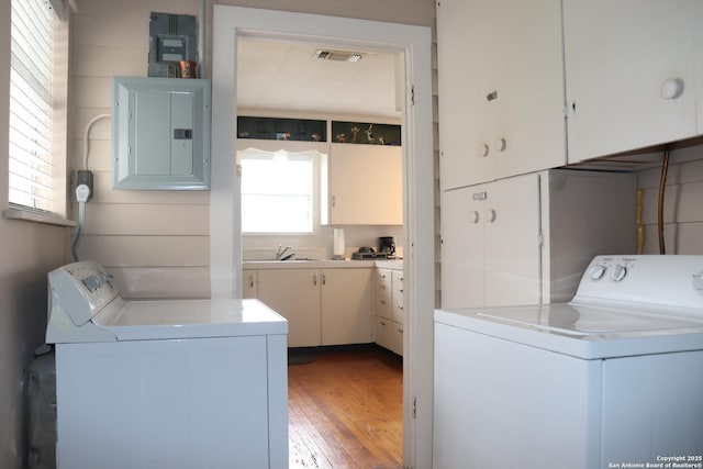 laundry area with sink, electric panel, cabinets, and washing machine and clothes dryer