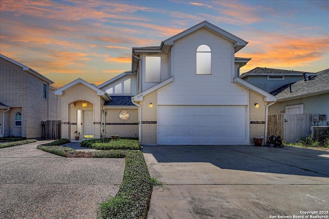 view of front of home with a garage, concrete driveway, brick siding, and fence