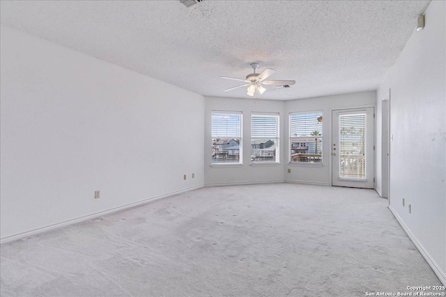 empty room with ceiling fan, light colored carpet, and a textured ceiling