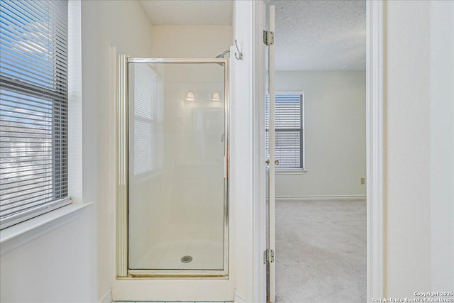 bathroom with a wealth of natural light, a textured ceiling, and walk in shower