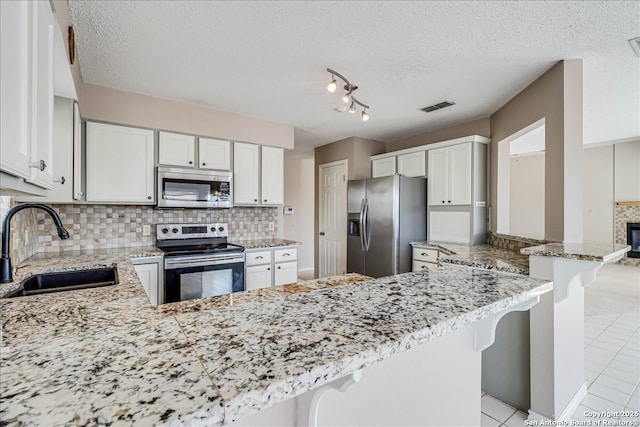 kitchen featuring sink, a breakfast bar area, appliances with stainless steel finishes, tasteful backsplash, and kitchen peninsula