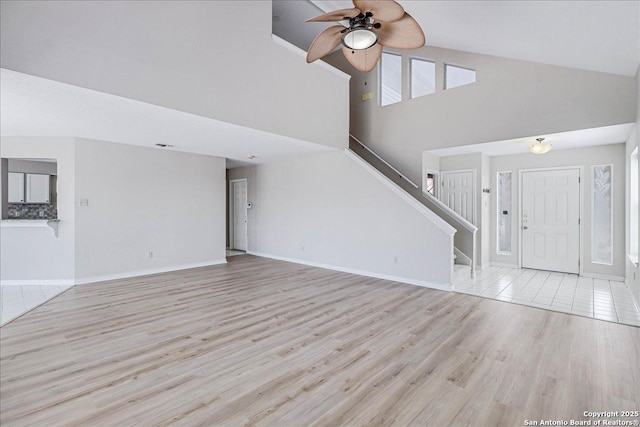 unfurnished living room featuring plenty of natural light, high vaulted ceiling, ceiling fan, and light wood-type flooring