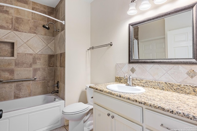 full bathroom with vanity, backsplash, tiled shower / bath, and toilet