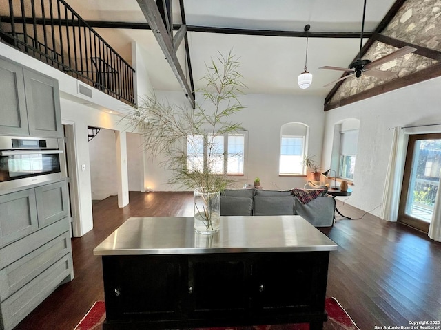 kitchen with stainless steel counters, high vaulted ceiling, stainless steel oven, and a kitchen island