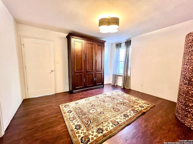 bedroom with dark hardwood / wood-style flooring and a textured ceiling