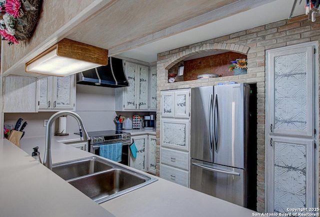 kitchen with sink, stainless steel appliances, white cabinets, brick wall, and exhaust hood