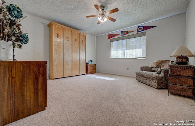 living area featuring ceiling fan, light colored carpet, and a textured ceiling