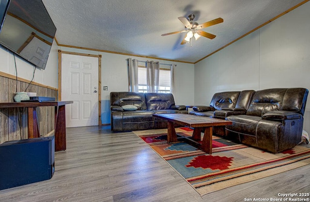 living room with ceiling fan, ornamental molding, hardwood / wood-style floors, and a textured ceiling