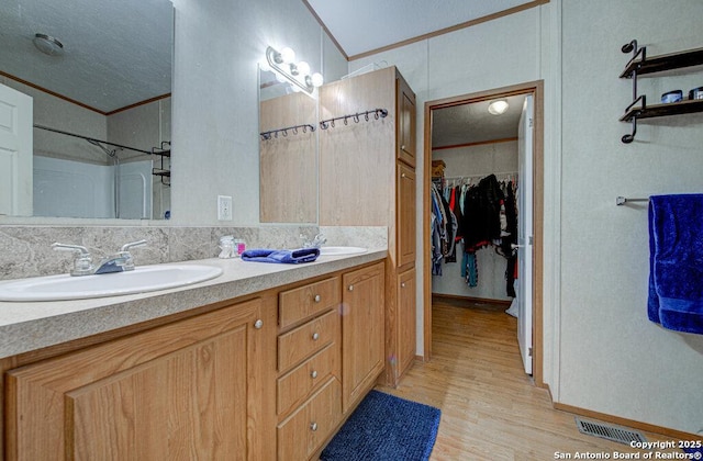 bathroom with ornamental molding, hardwood / wood-style floors, vanity, and a textured ceiling