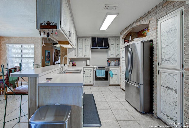 kitchen with sink, a kitchen breakfast bar, kitchen peninsula, stainless steel appliances, and wall chimney range hood