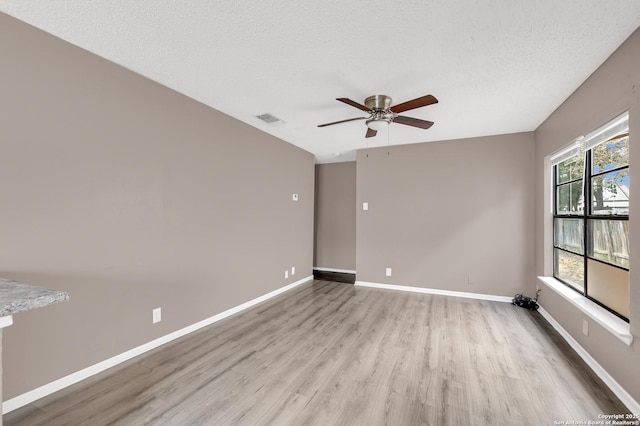 unfurnished room with ceiling fan, light hardwood / wood-style flooring, and a textured ceiling