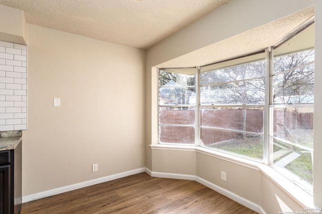 unfurnished dining area with hardwood / wood-style floors and a textured ceiling