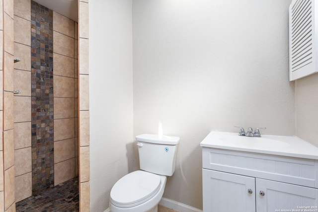 bathroom with vanity, tiled shower, and toilet