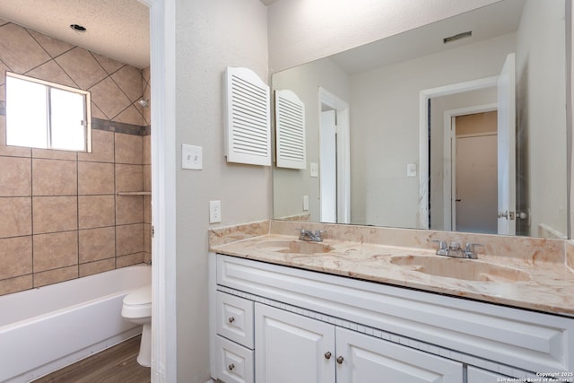 full bathroom featuring vanity, toilet, tiled shower / bath combo, and hardwood / wood-style floors