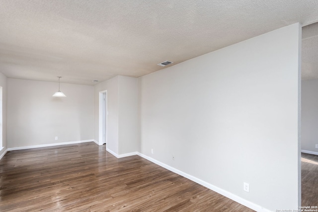 spare room featuring dark wood-type flooring and a textured ceiling