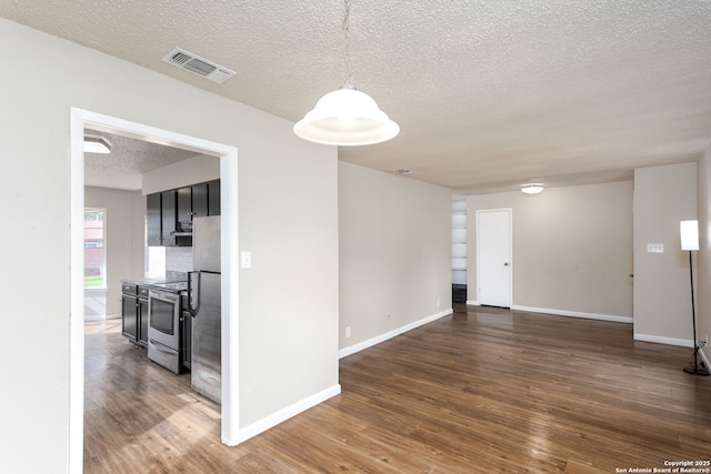 unfurnished room with a textured ceiling and dark hardwood / wood-style flooring