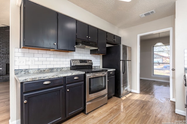 kitchen with decorative light fixtures, a textured ceiling, appliances with stainless steel finishes, light hardwood / wood-style floors, and decorative backsplash