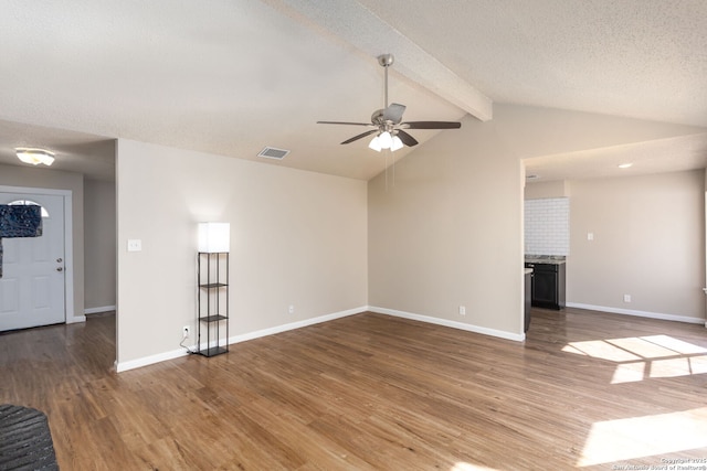 unfurnished living room featuring ceiling fan, vaulted ceiling with beams, dark wood-type flooring, and a textured ceiling