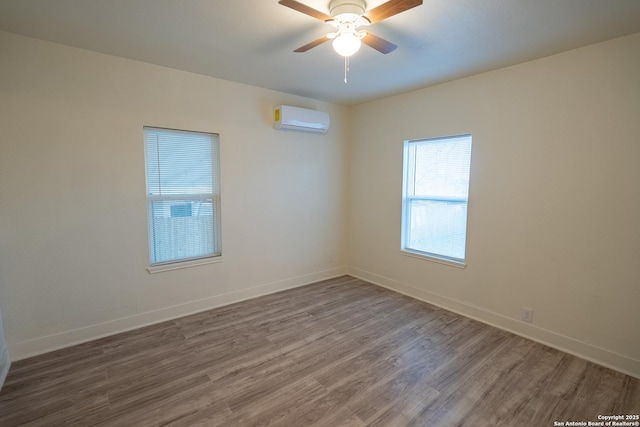 empty room featuring hardwood / wood-style flooring, a wall mounted AC, and ceiling fan