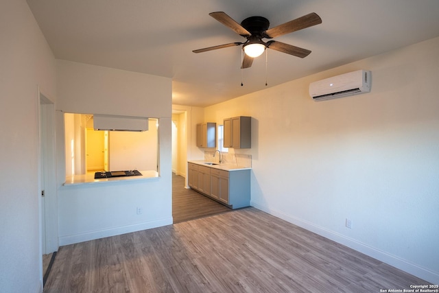 unfurnished living room featuring a wall mounted air conditioner, hardwood / wood-style flooring, sink, and ceiling fan