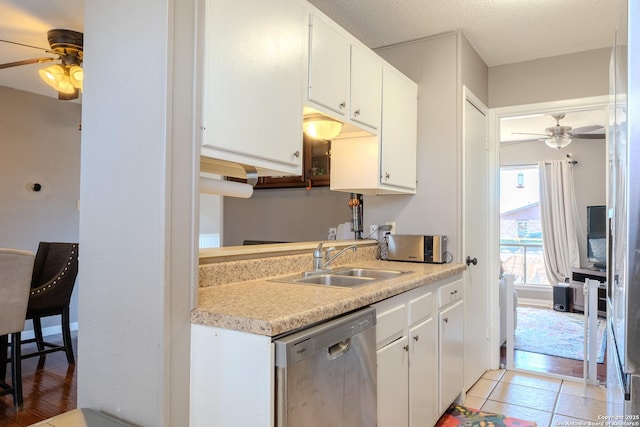 kitchen featuring stainless steel dishwasher, light tile patterned floors, sink, and white cabinets