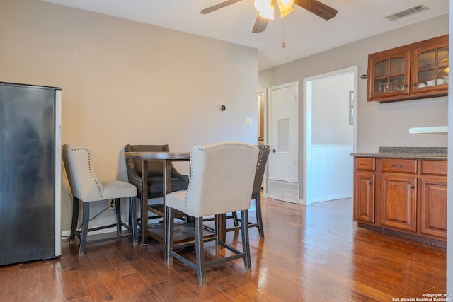 dining room featuring baseboards, dark wood-type flooring, visible vents, and a ceiling fan