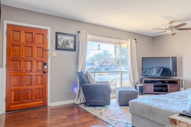 living room featuring ceiling fan, dark hardwood / wood-style floors, and a textured ceiling