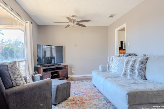 living area featuring ceiling fan, visible vents, light wood-style flooring, and a wealth of natural light