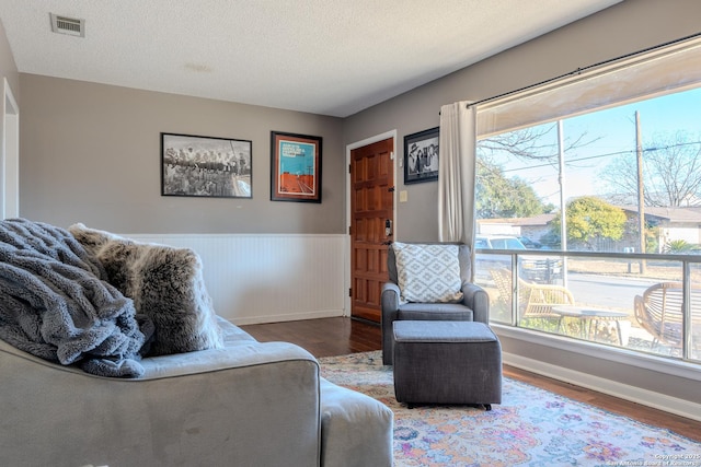 sitting room featuring a wealth of natural light, a wainscoted wall, and wood finished floors