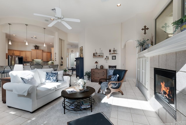 tiled living room with ceiling fan, lofted ceiling, and a fireplace