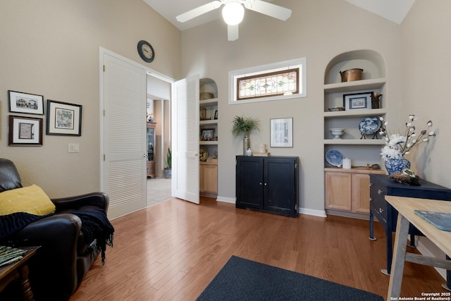 home office featuring vaulted ceiling, hardwood / wood-style floors, ceiling fan, and built in shelves