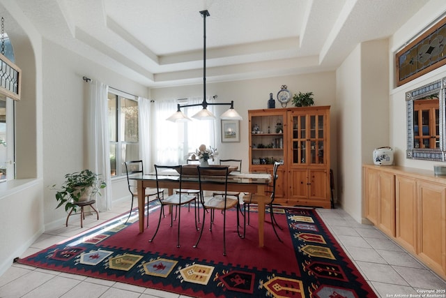 dining space featuring a tray ceiling, a textured ceiling, and light tile patterned floors